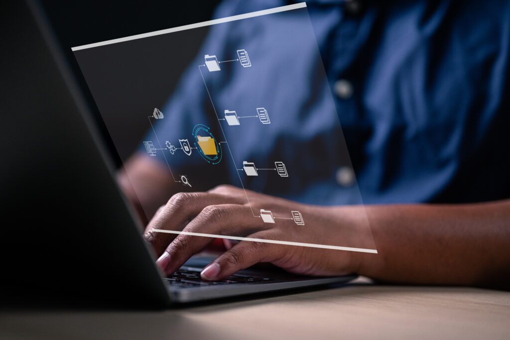 A close-up of hands at a laptop with an overlay above the hands displaying files on the screen